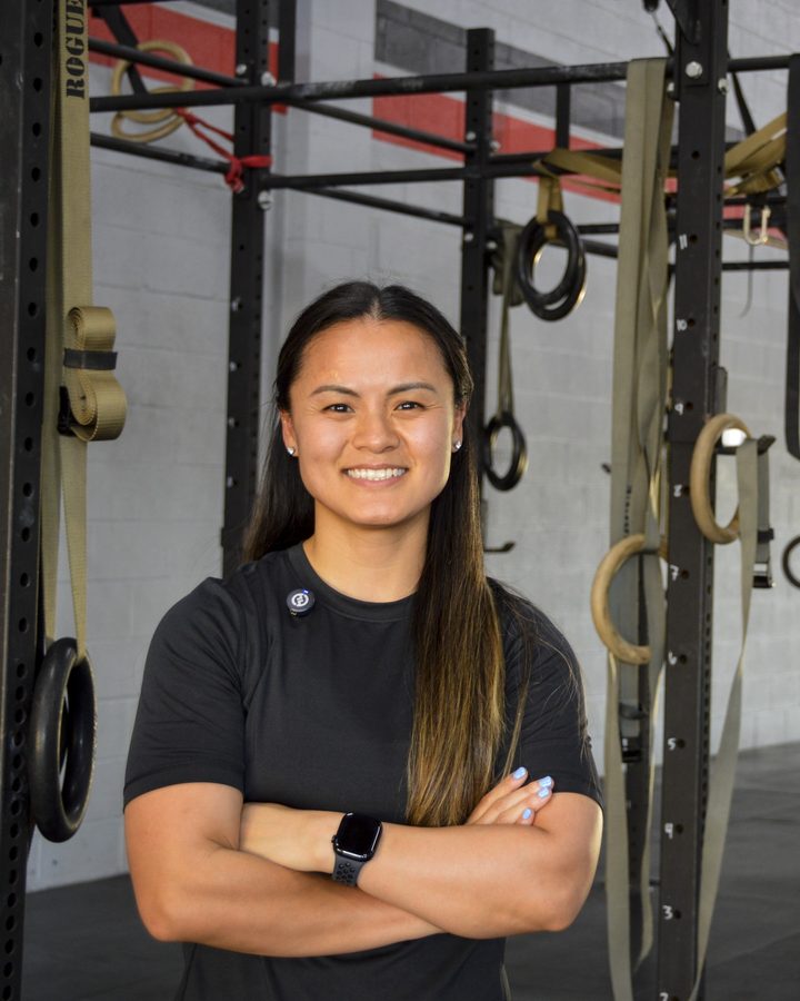Portrait of Dr. Amy Driessen, PT, DPT, CSCS, CDNS, smiling with her arms folded in front of a gym rig.